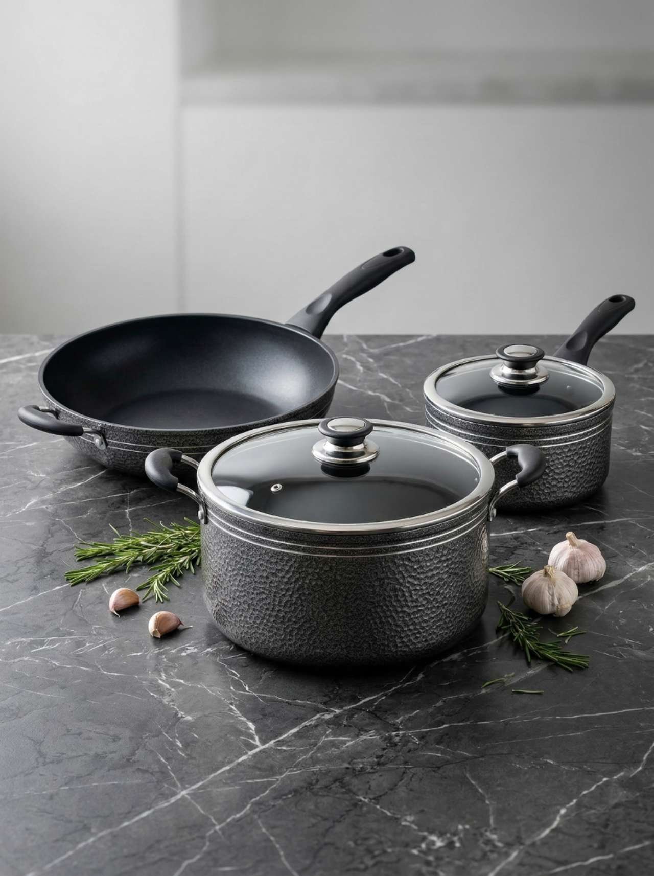 Koozina black cookware set styled on a stone countertop